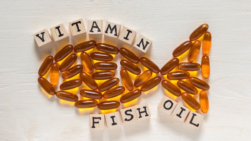 Halolaj kapszulák és betűk formálják a 'fish oil' szót, egészséges táplálkozás.