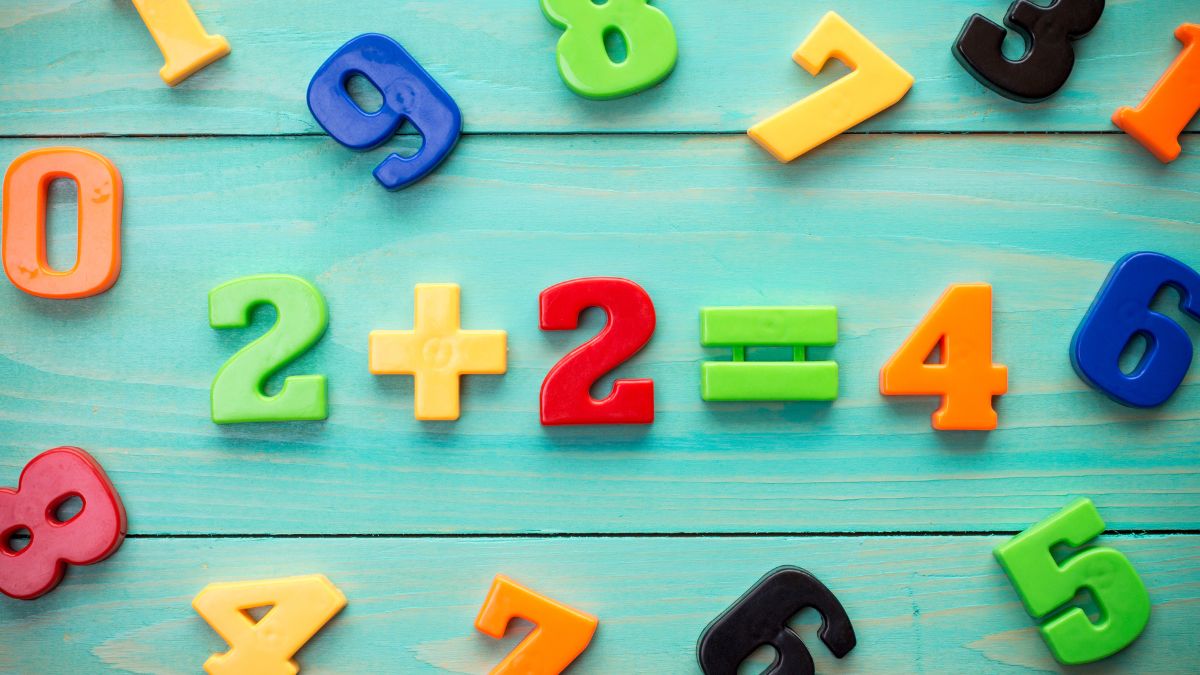Színes műanyag számok és matematikai műveletek egy zöldes háttéren.